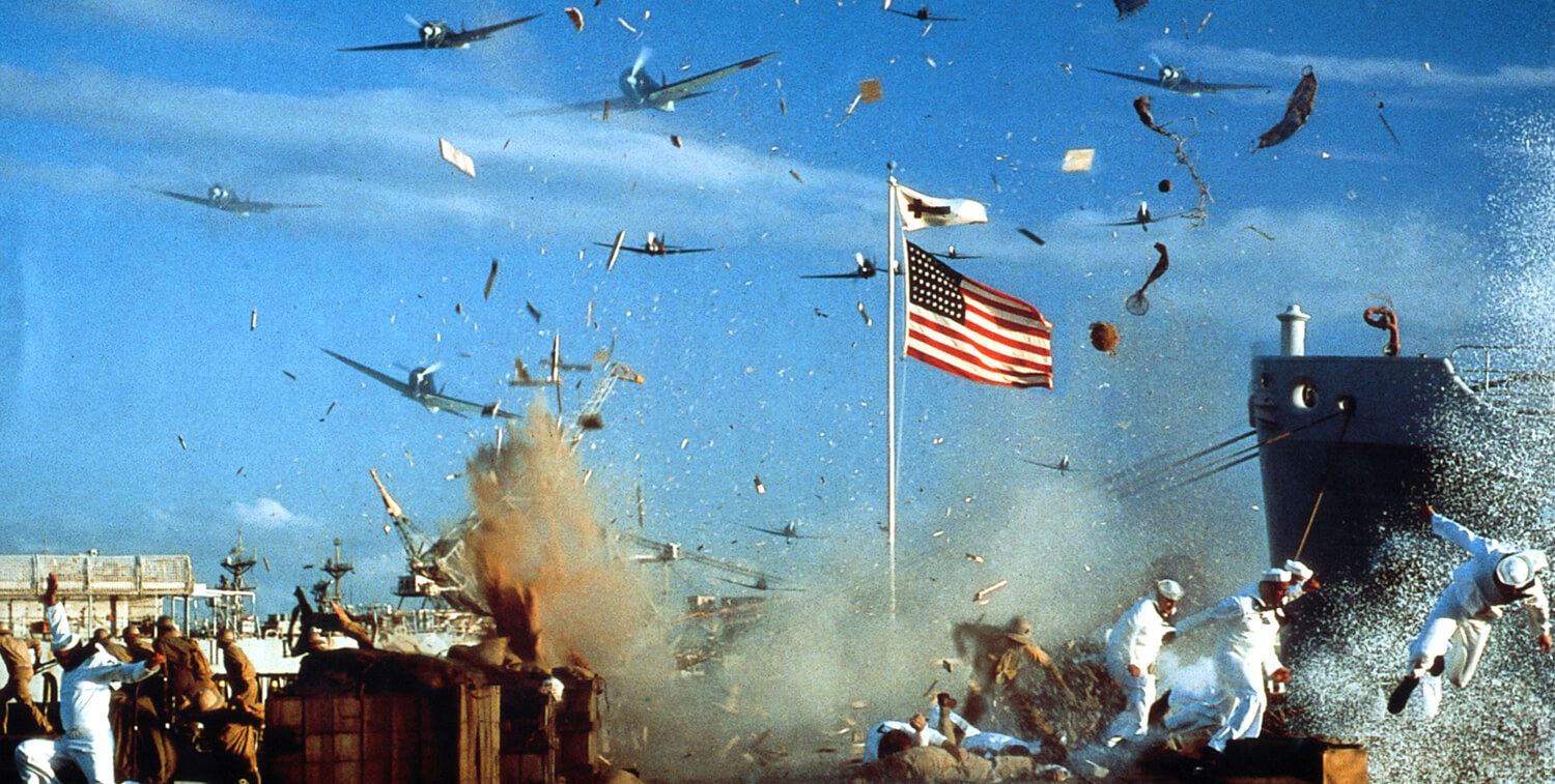 Planes fly overhead while bombs explode with debris, soldiers trying to run from the wreckage, american flag and white flag with cross wave in the wind in the center