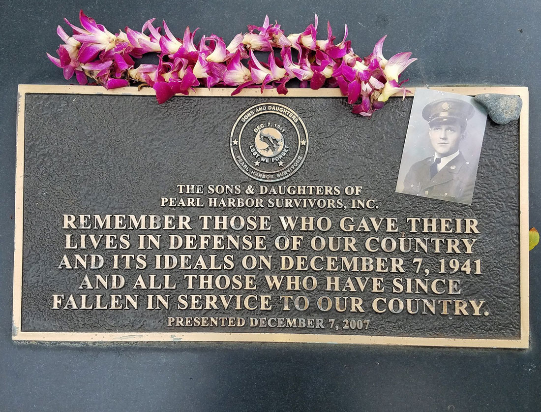 Plaque with lei of flowers and an old photograph of a soldier
